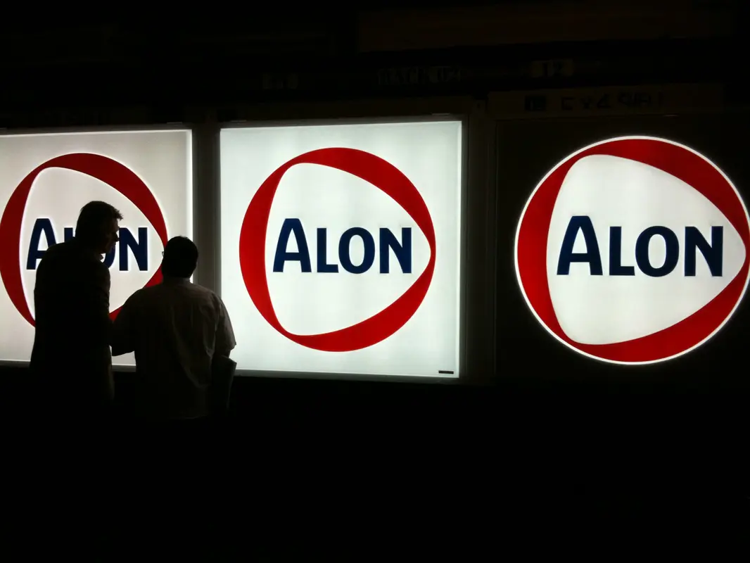 Backlit Alon signs with two silhouetted people.