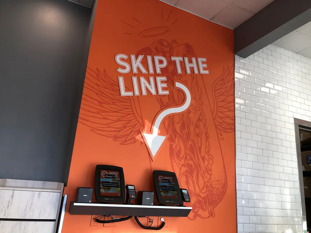 Skip the line" sign with kiosks.